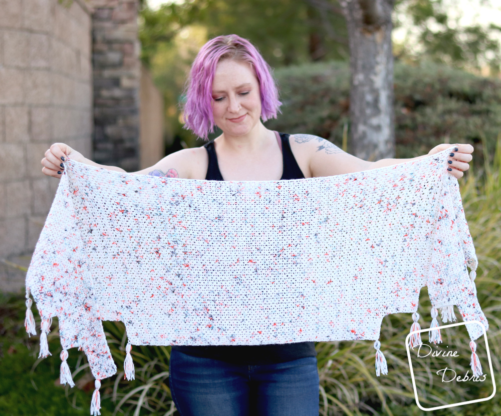 [image description]White woman with purple hair holds a white Lois Shawl out in front of her.