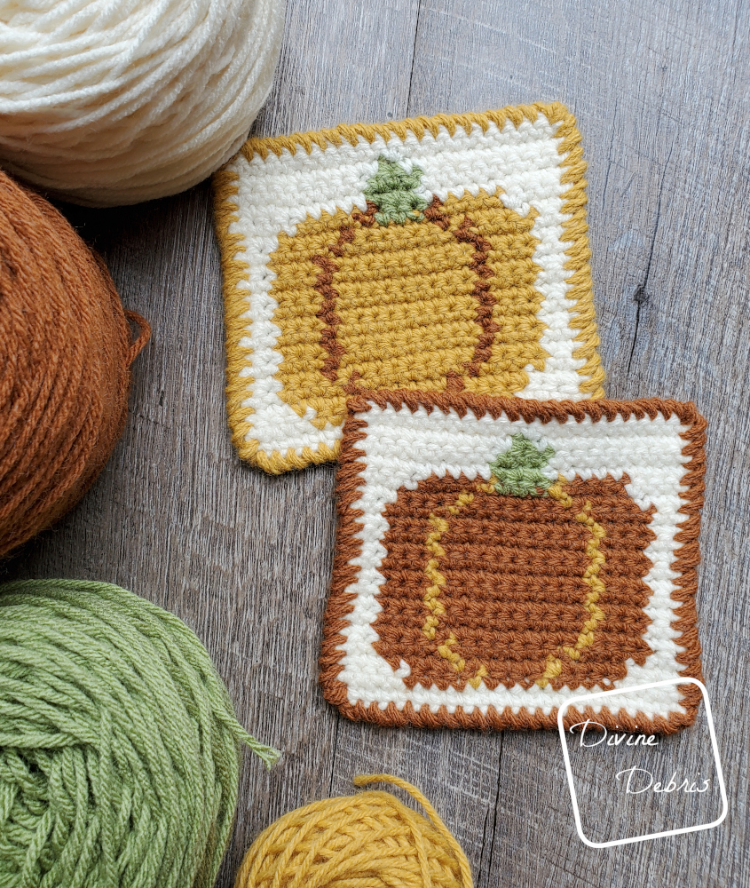 [Image description} top down view of 2 Fall Pumpkin Coasters on a wood grain background, with cakes of yarn along the left side of the frame.