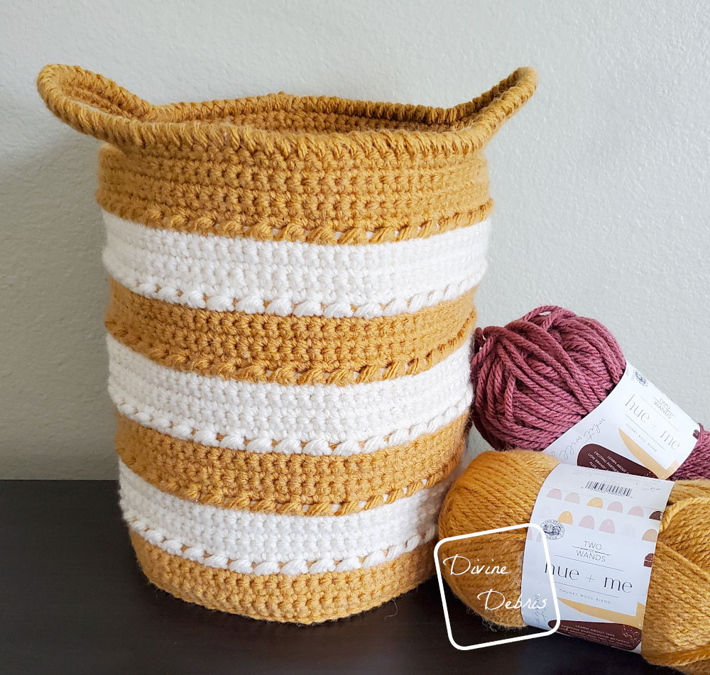 [Image description] Yellow and white striped Claire Basket sits on a black shelf against a cream background, with 2 skeins of yarn on the right side of the photo