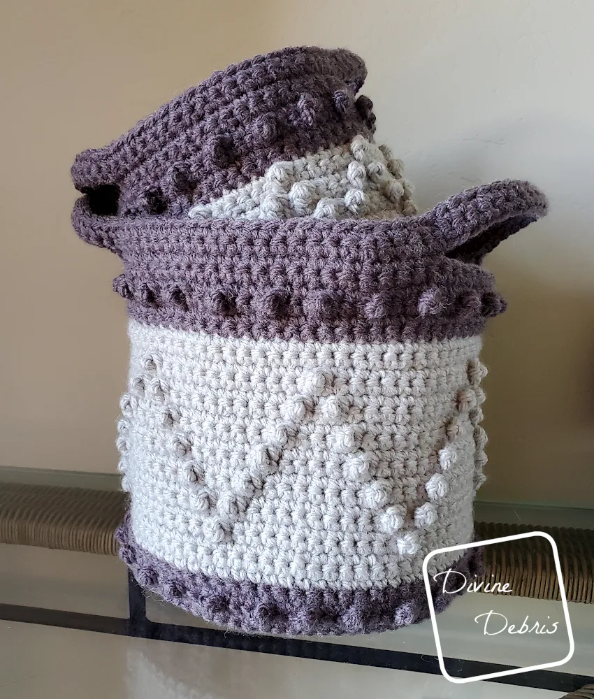 [image description] Photo of the Berry Stitch Baskets, the small one tucked in the big one, sitting on a glass table against a tan wall