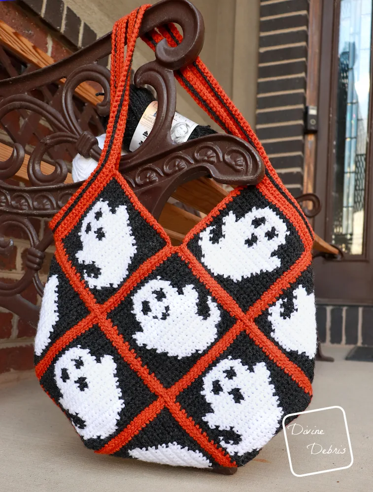 [Image description] The Glenda Ghost  Bag hangs off a bench in front of a brick wall 