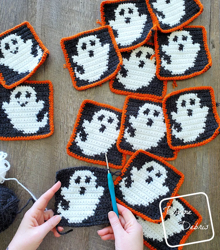 [Image description] Top down view some of the unseamed squares for the Glenda Ghost Bag crochet pattern, with a white woman's hands holding one in the bottom left corner